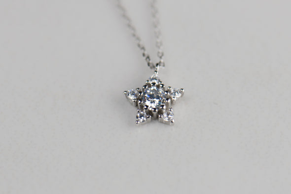 Collar de cadena plateado con estrella en zirconias sobre superficie blanca
