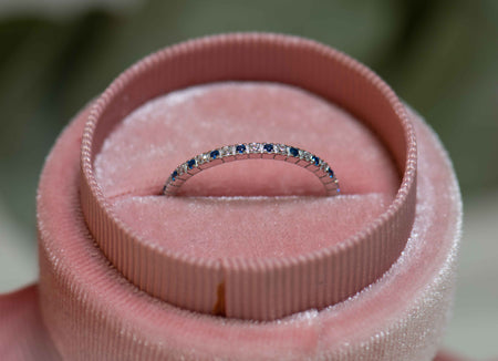 Anillo en plata 925 con zirconias blancas y azules pequeñas incrustadas al rededor de la argolla exhibido dentro una caja de anillo rosa en Guatemala