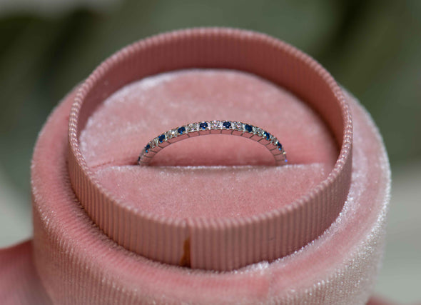 Anillo en plata 925 con zirconias blancas y azules pequeñas incrustadas al rededor de la argolla exhibido dentro una caja de anillo rosa en Guatemala