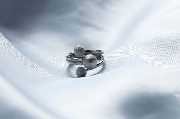 Anillo de plata 925 ajustable desde el frente con tres esferas de diferentes tamaños exhibido sobre una seda blanca