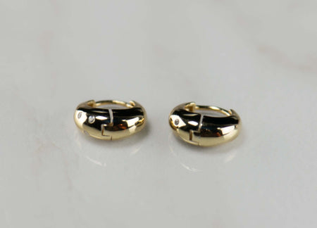 Argollas de plata 925 con baño de oro 18k con zirconias sobre superficie blanca vista cerana