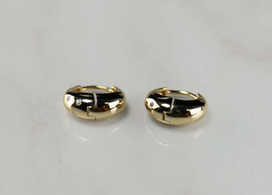 Argollas de plata 925 con baño de oro 18k con zirconias sobre superficie blanca vista cerana