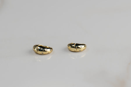 Argollas de plata 925 con baño de oro 18k con zirconias sobre superficie blanca