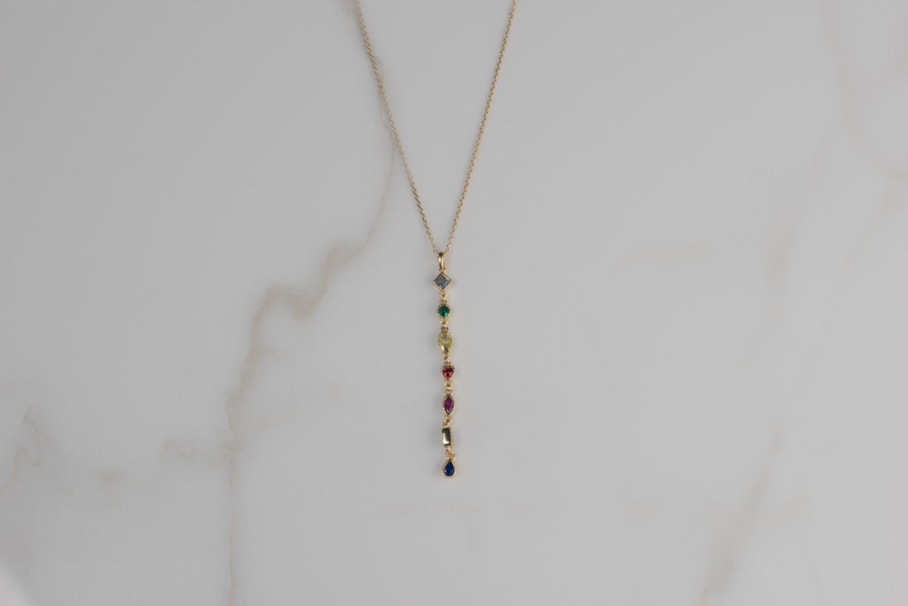 Detalle de collar con cadena y pendiente de piedras de colores con baño de oro 18k