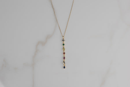 Detalle de collar con cadena y pendiente de piedras de colores con baño de oro 18k