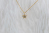 Collar de cadena dorado con estrella en zirconias sobre superficie blanca