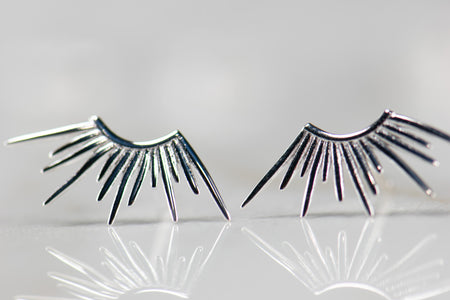Detalle de aretes en forma de rayos de sol en plata 925