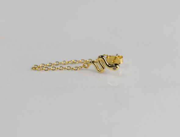 Arete piercing de plata 925 con baño de oro 18k en forma de serpiente y cadena colgante exhibido sobre superficie blanca