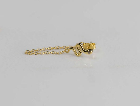 Arete piercing de plata 925 con baño de oro 18k en forma de serpiente y cadena colgante exhibido sobre superficie blanca