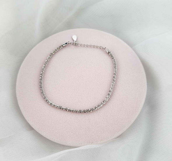 Pulsera color plata sobre superficie rosa