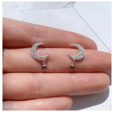 Aretes de Plata 925 en forma de luna con zirconias y pequeña estrella colgante exhibidos sobre una mano