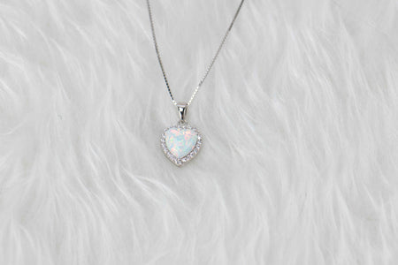 Detalle de collar en plata 925 y pendiente de ópalo sintético en forma de corazón y marco incrustado en zirconias