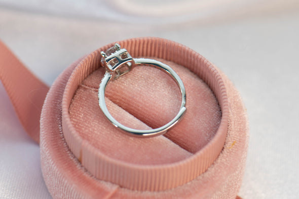 Anillo de plata 925 ajustable con zirconia central grande y zirconias pequeñas incrustadas en la banda exhibido dentro de caja de anillo rosa desde atrás para ver detalle de sujeción de piedra central