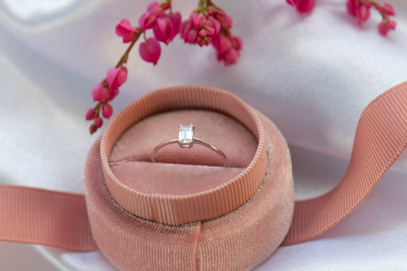 Anillo liso en plata 925 con piedra central cuadrada zirconia blanca sobre caja de joyas rosa