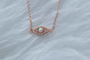 Detalle de collar con cadena y pendiente de ojo con ópalo sintético con baño de oro rosa 18k