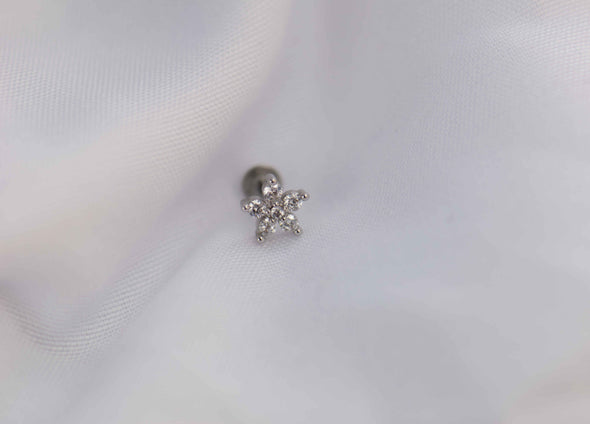 Detalle de arete piercing de flor color plata con piedras zirconias blancas