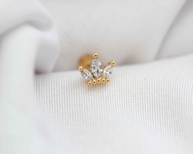 Detalle de arete piercing de corona color oro con piedras zirconias blancas