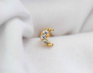 Detalle de arete piercing de Luna color oro con piedras zirconias blancas