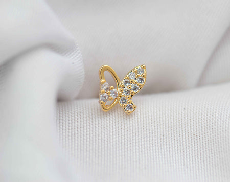 Arete piercing de mariposa color dorado con zirconias blancas sobre seda blanca