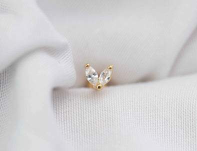Detalle de arete piercing de corazón color oro con piedras zirconias blancas