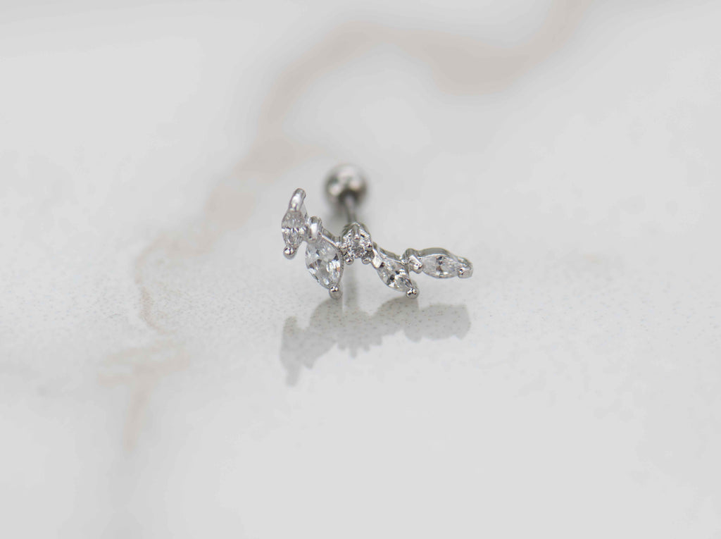 Detalle de arete piercing de racimo de hojas color plata con piedras zirconias blancas