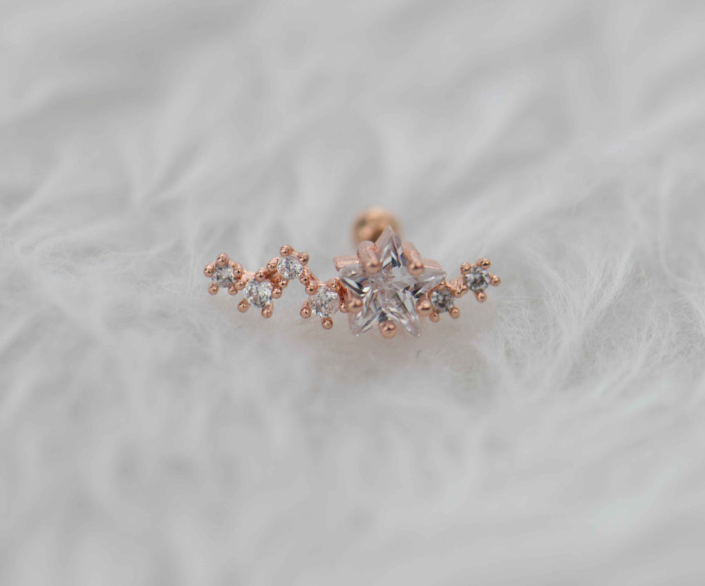 Arete piercing en acero inoxidable con frente de cobre y estrella en circonita en color oro rosa exhibido en Guatemala