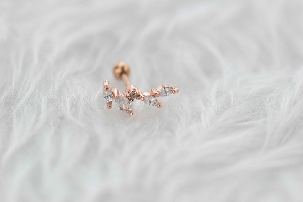 Detalle de arete piercing de racimo de hojas color oro rosa con piedras zirconias blancas