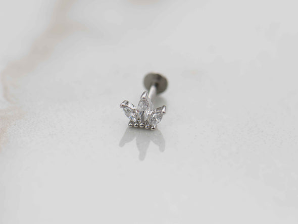 Detalle de arete piercing de corona color plata con piedras zirconias blancas