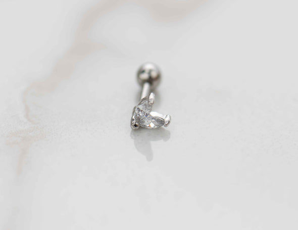 Detalle de arete piercing de corazón color plata con piedras zirconias blancas