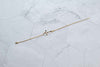 Pulera cadena delicada en color oro con cruz dorada extendida sobre superficie de mármol
