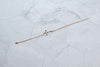 Pulera cadena delicada en color oro con cruz dorada extendida sobre superficie de mármol