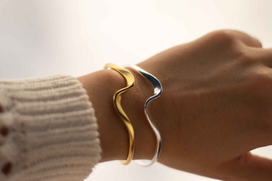 Mano con brazalete curvo en plata 925 y brazalete curvo con baño de oro 18k