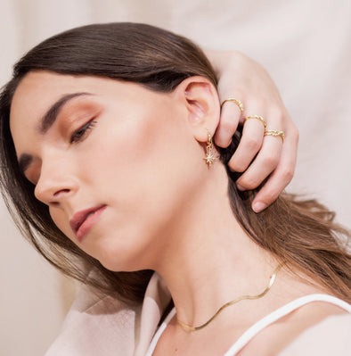 Modelo con Aretes de argolla pequeña en baño de oro 18k con estrella lucero de zirconias blancas