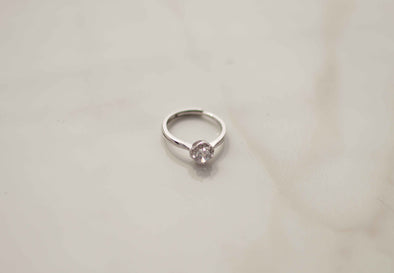 Anillo de plata 925 ajustable con zirconia central grande exhibido sobre superficie blanca