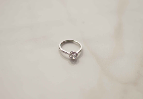 Anillo de plata 925 ajustable con zirconia central grande exhibido sobre superficie blanca