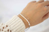 mano modelando pulsera color plata doble con cadena delicada y otra con piedras tipo perlas