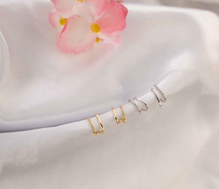 Par de aretes color plata con zirconias incrustadas blancas y par de aretes dorados con zirconias incrustadas blancas sobre seda blanca
