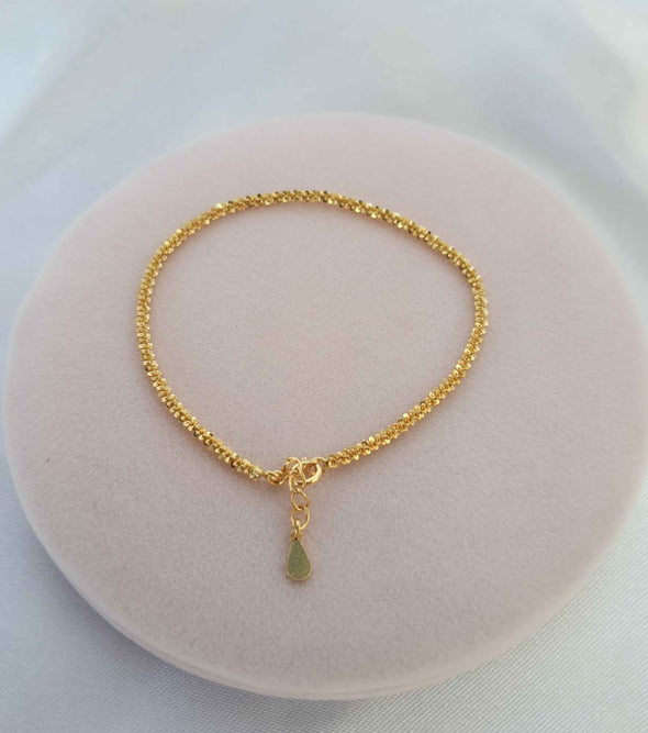 Pulsera color dorado sobre superficie rosa