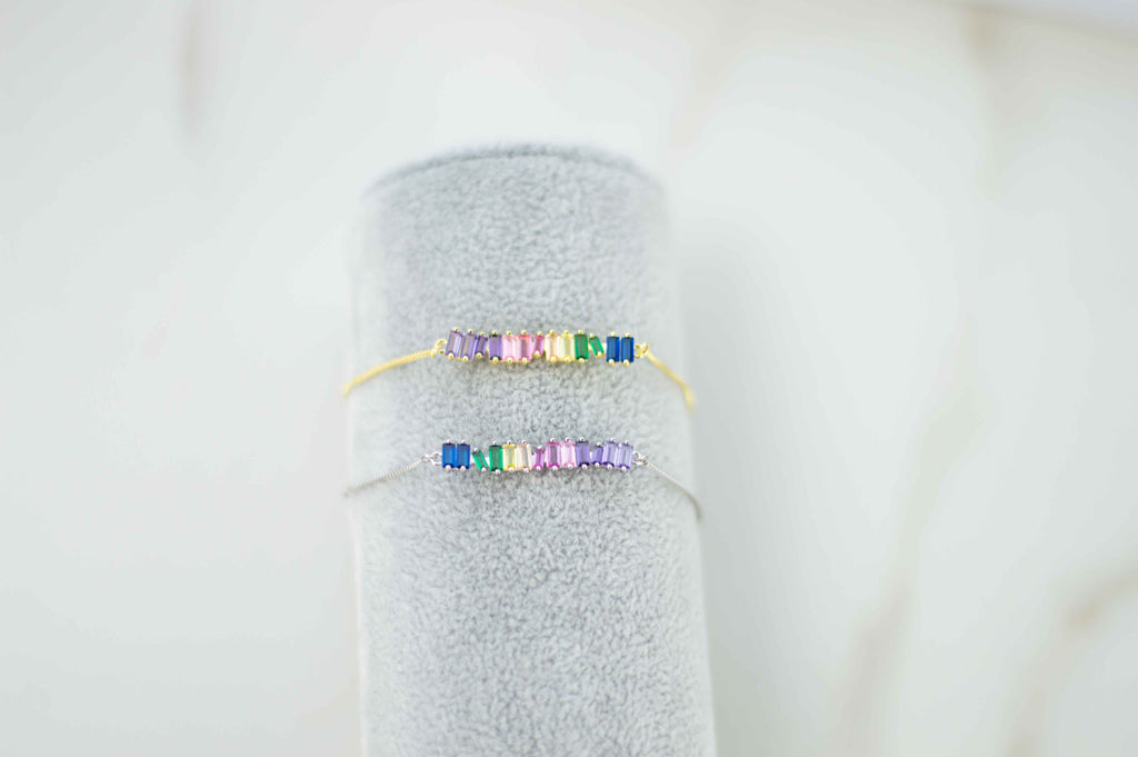 Exhibición gris con pulseras brazalete color oro y plata con zirconias de colores