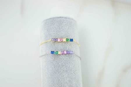 Exhibición gris con pulseras brazalete color oro y plata con zirconias de colores