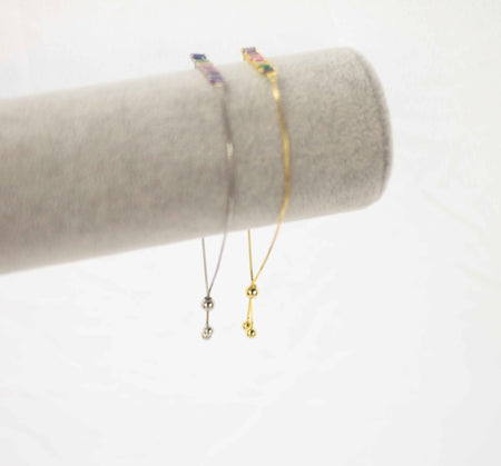 Exhibición gris con pulseras brazalete color oro y plata con zirconias de colores con cierre en esfera
