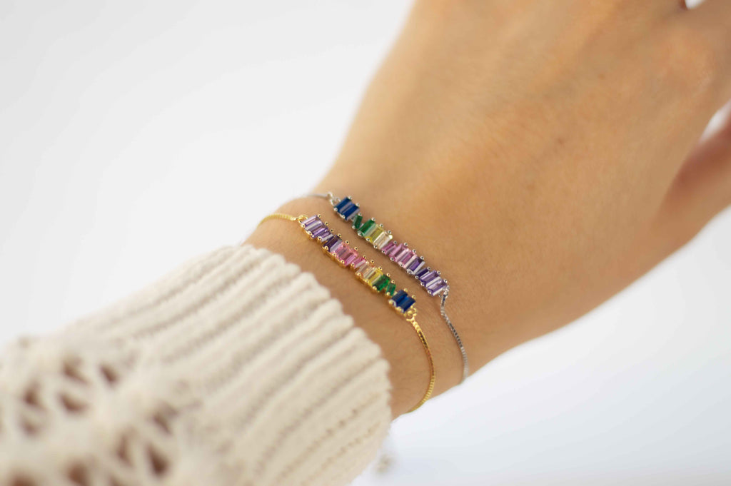 Mano con pulseras brazalete color oro y plata con zirconias de colores