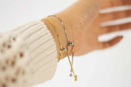 Mano con pulseras brazalete color oro y plata detalle cierre en esfera ajustable