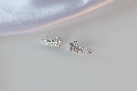 Aretes de plata 925 en formade recimo de hojas con Zirconias pequeñas exhibidos sobre superficie blanca