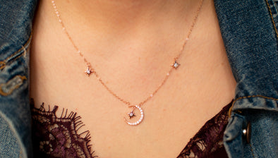 Modelo con collar cadena color oro rosa y pendientes de luna y estrellas incrustados con zirconias