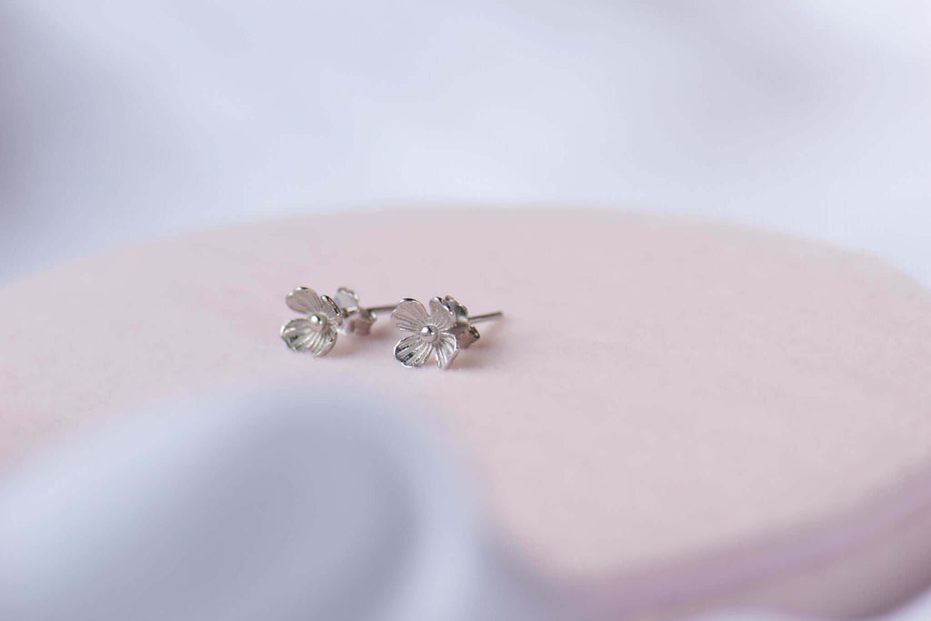 Aretes de flor pequeña en plata 925 exhibidos sobre superficie blanca
