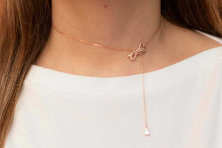 Modelo usando collar tipo choker con moña color oro rosa