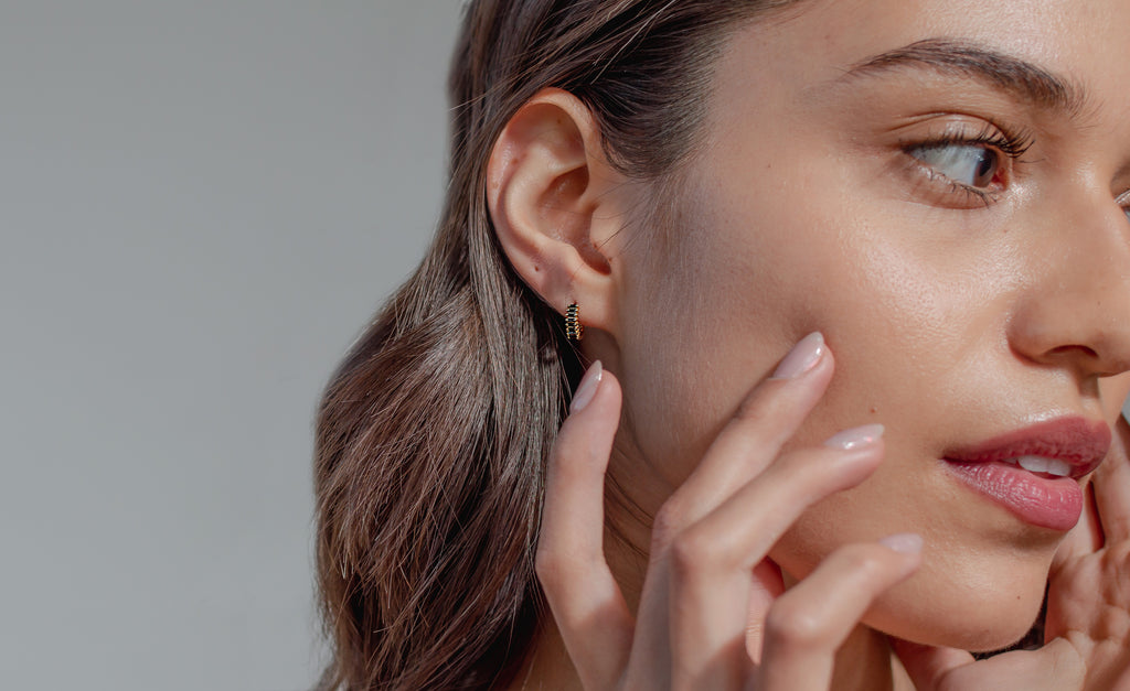 Modelo con Aretes de argolla pequeña en baño de oro 18k con zirconias negras