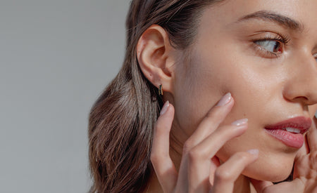 Modelo con Aretes de argolla pequeña en baño de oro 18k con zirconias negras