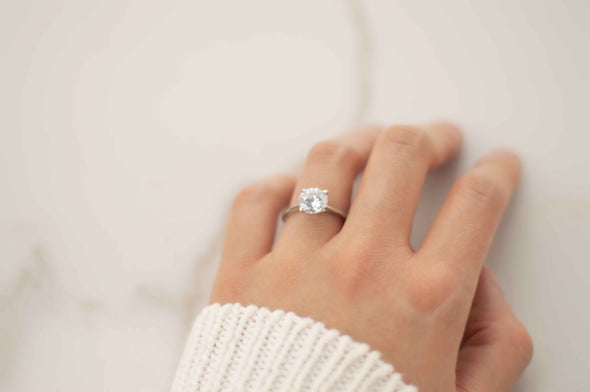 Mano con Anillo liso en plata 925 con Zirconia con central corte de diamante